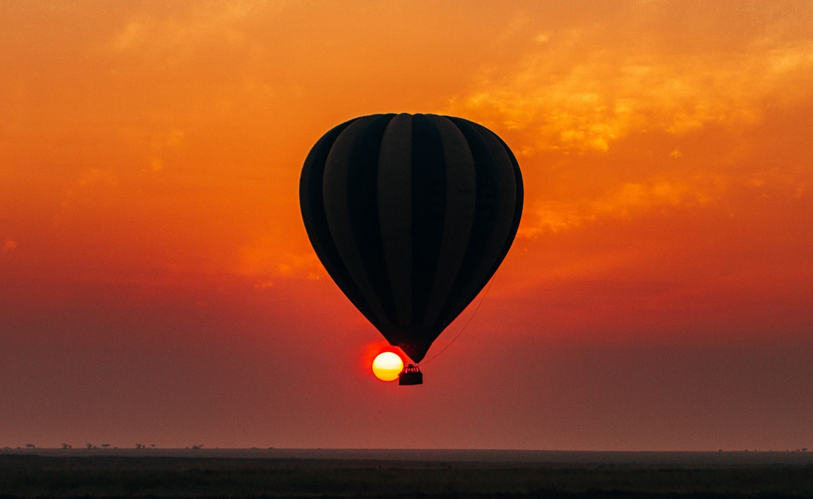 A balloon drifting across the rising sun