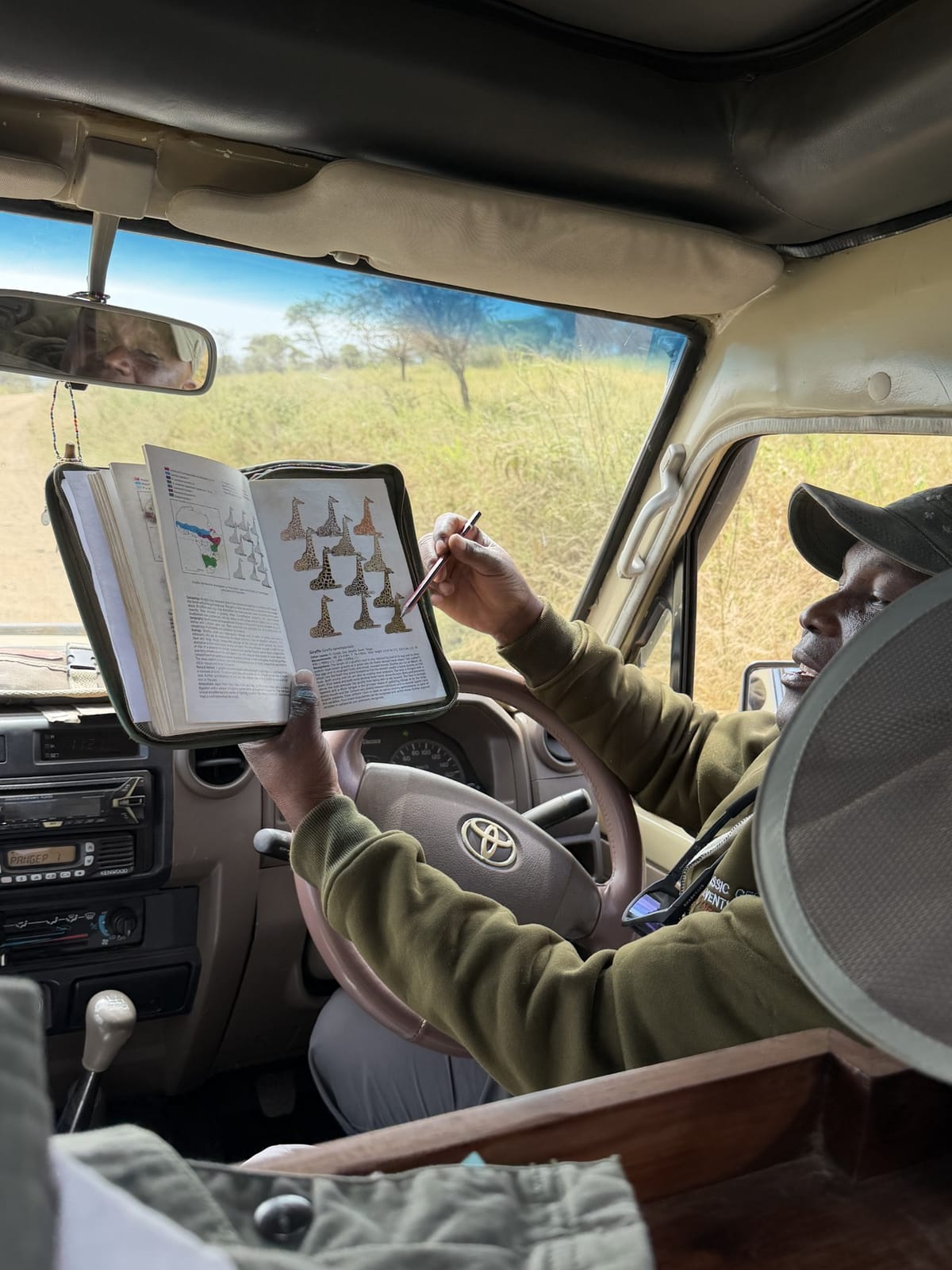 A guide checking a field guide from the driver's seat