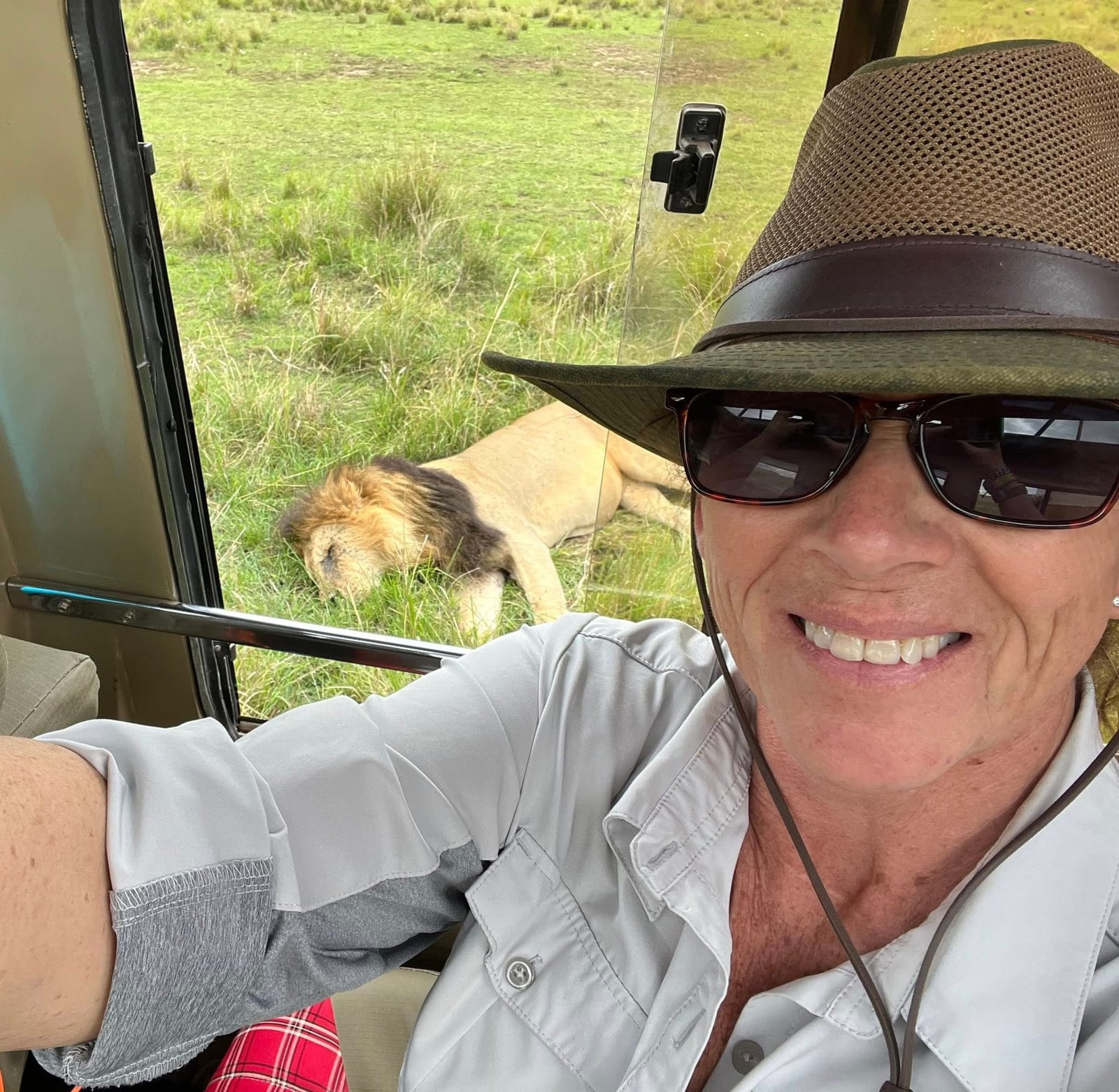 Nancy on a game drive with a lion behind