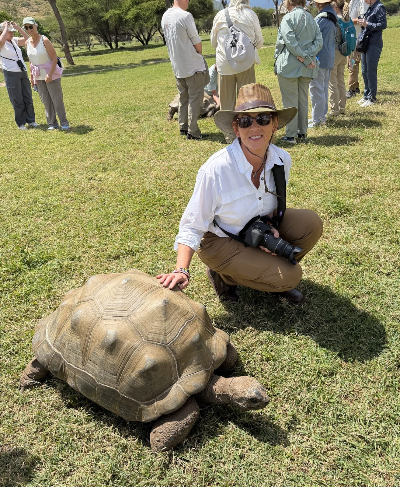 Nancy crouching beside a giant tortoise