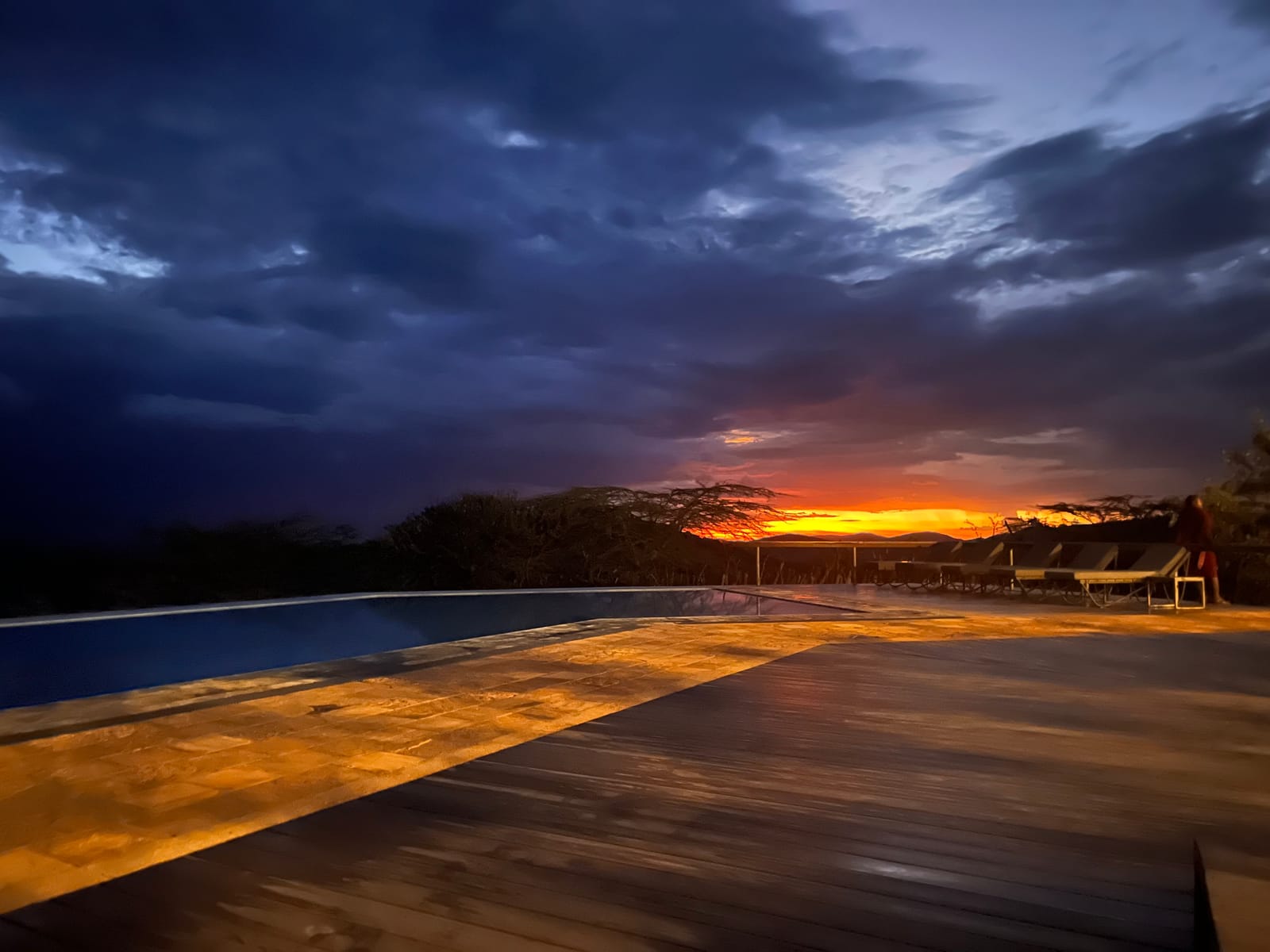 Sunset glowing beyond a lodge pool under stormy skies