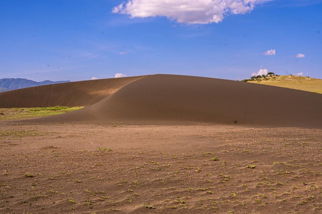 The dark volcanic-ash shifting sand dune under a blue sky